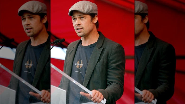 Brad Pitt speaks at the unveiling of his Make it Right homes in a hat and blazer