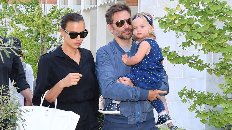 Irina Shayk walks next to Bradley Cooper holding Lea