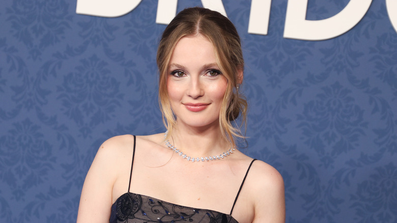 Wearing a lacy black outfit, Hannah Dodd flashes a gentle smile on the red carpet.