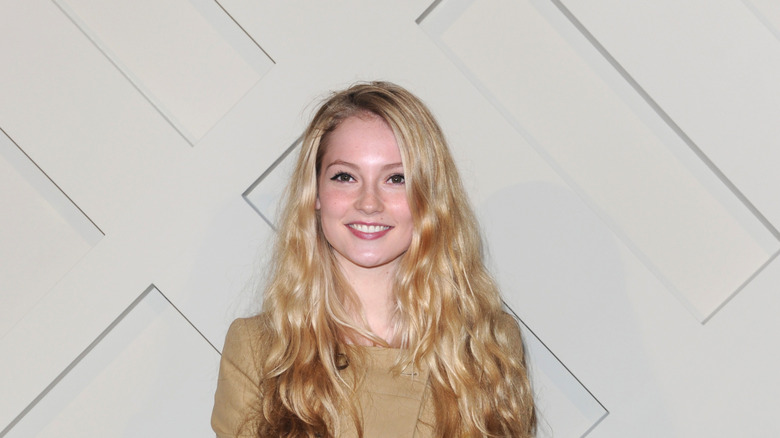 Sporting a beige look and blonde hair, Hannah Dodd flashes a wide smile.