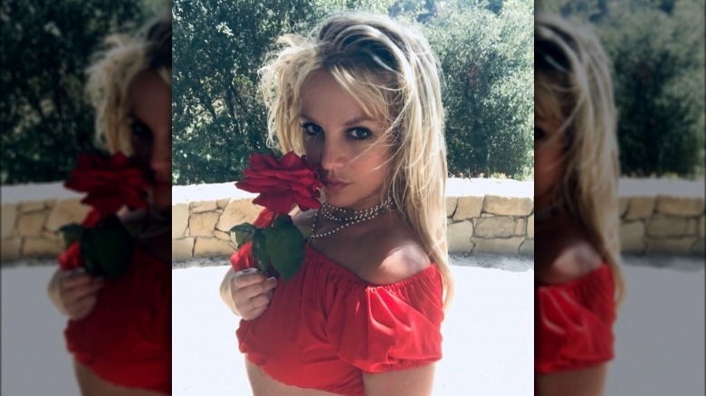 Britney holding a rose in a red top on Instagram