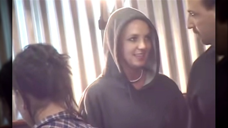 Britney without hair, in hoodie at tattoo parlor