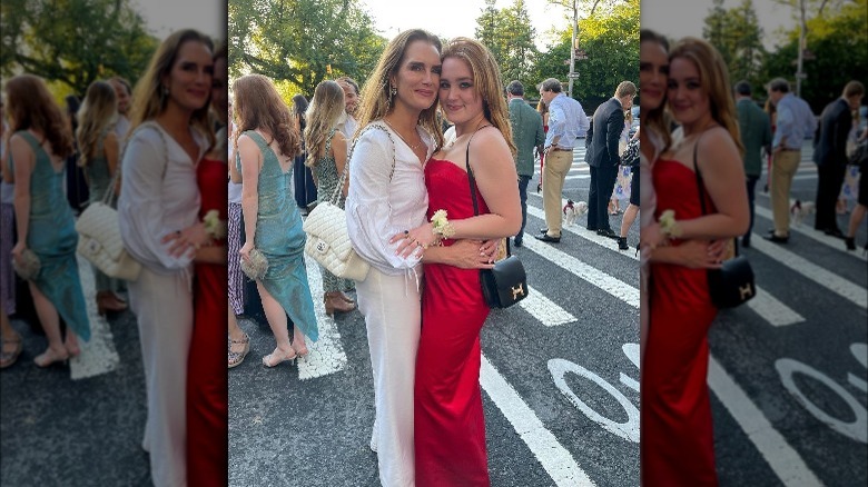 Brooke Shields, wearing white pants outfit, smiling, hugging her daughter, Rowan Francis Henchy, smiling, wearing her red dress, at prom