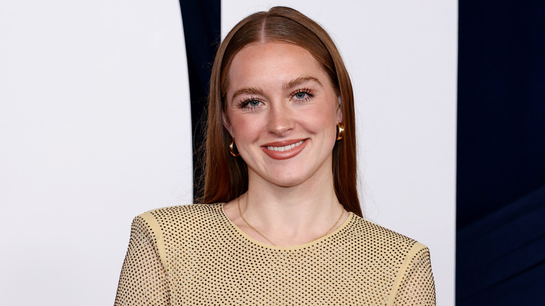 Rowan Henchy smiling and posing in a beige dress covered with rhinestones.