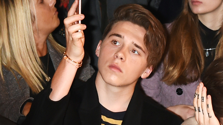 Brooklyn Beckham looking up at phone