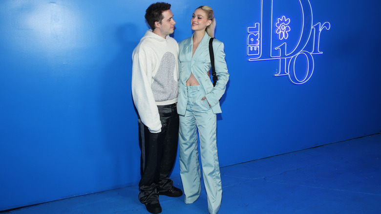 Brooklyn Beckham and Nicola Peltz smiling and looking at each other at the Dior Men's Spring/Summer 2023 Collection in 2022
