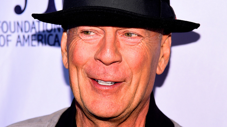 Bruce Willis smiling in black fedora