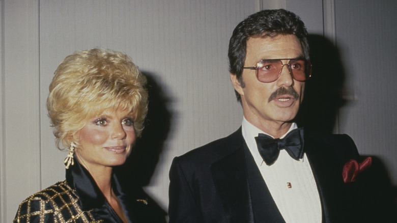 Loni Anderson and Burt Reynolds pose in a black and gold coat and tuxedo, respectively, in 1987.