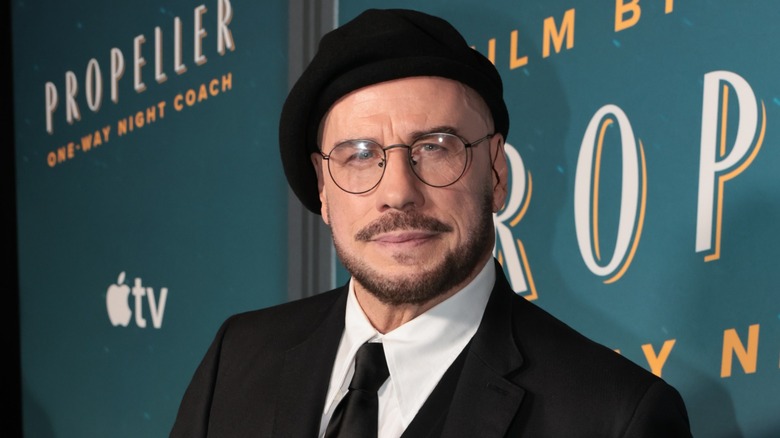 John Travolta posing at a premiere for "Propeller One-Way Night Coach."