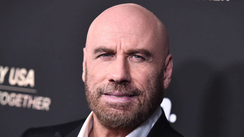 John Travolta posing on the red carpet with a shaved head.
