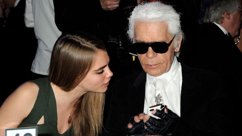 Cara Delevingne and Karl Lagerfeld, sitting at a table