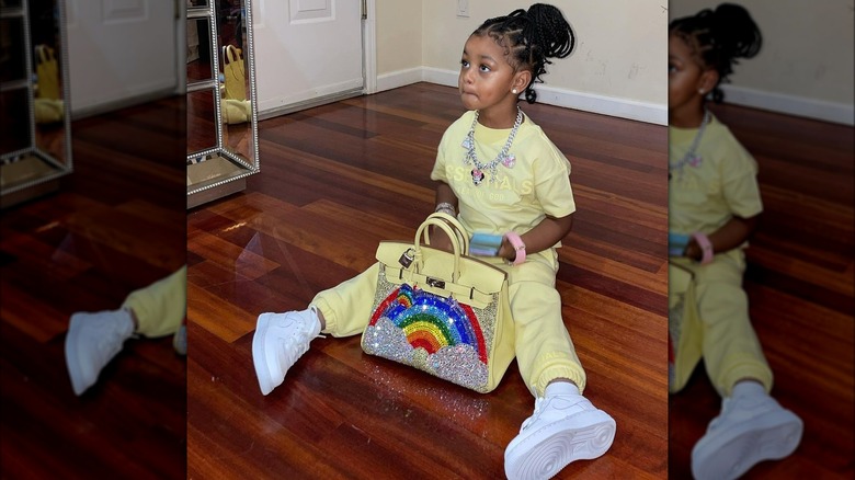 Kulture Kiari Cephus seated on floor with purse