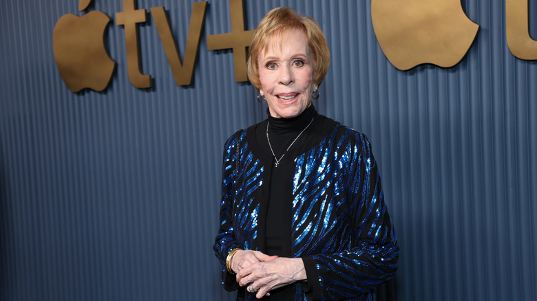 Carol Burnett posing in a sparkly blue jacket at an Apple TV event.