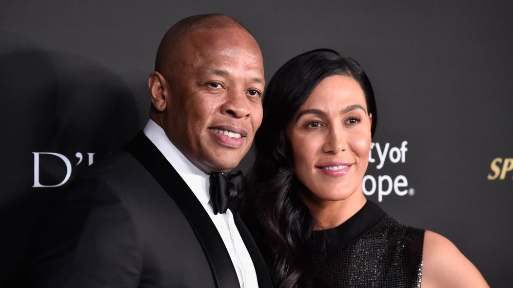 Dr. Dre and Nicole Young, posing arm-in-arm and smiling on the red carpet