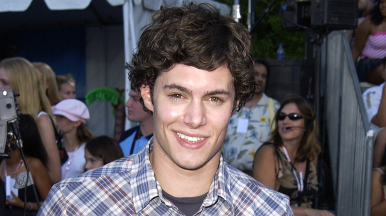 Adam Brody smiling while standing on a red carpet