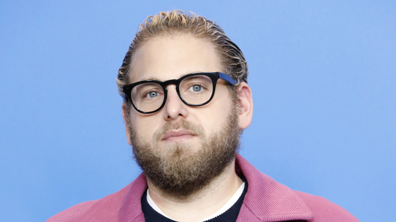 Jonah Hill wearing glasses with a blue background