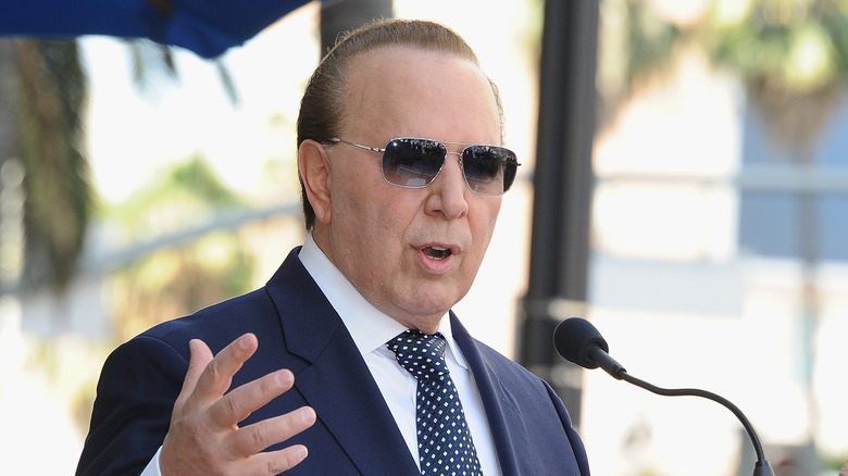 Tommy Mottola speaking at a podium, sunglasses on