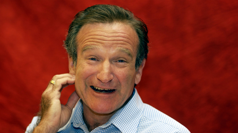 Robin Williams with hand to cheek smiling at a press conference for One Hour Photo