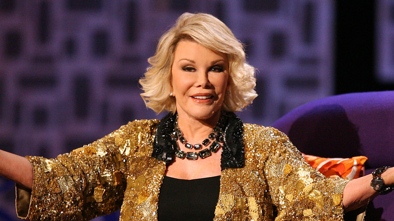 Joan Rivers extending her arms and wearing a gold sequinned top