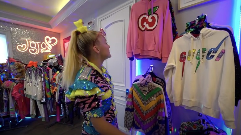 JoJo Siwa looking at Gucci sweatshirts in her closet