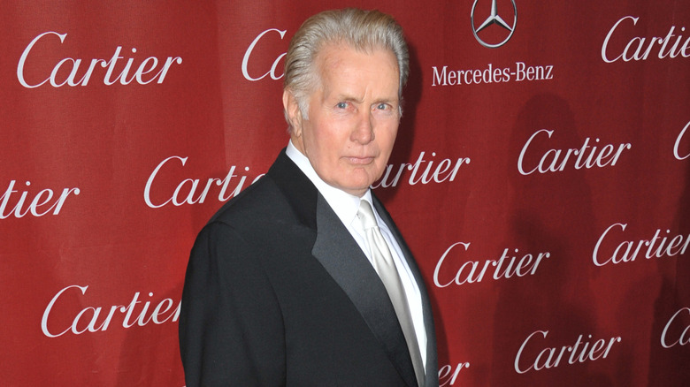 Martin Sheen standing in front of a red wall