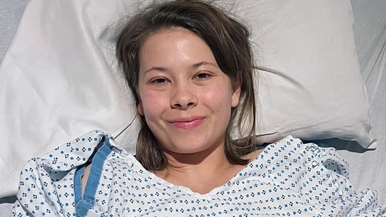 Bindi Irwin smiling in hospital bed and gown