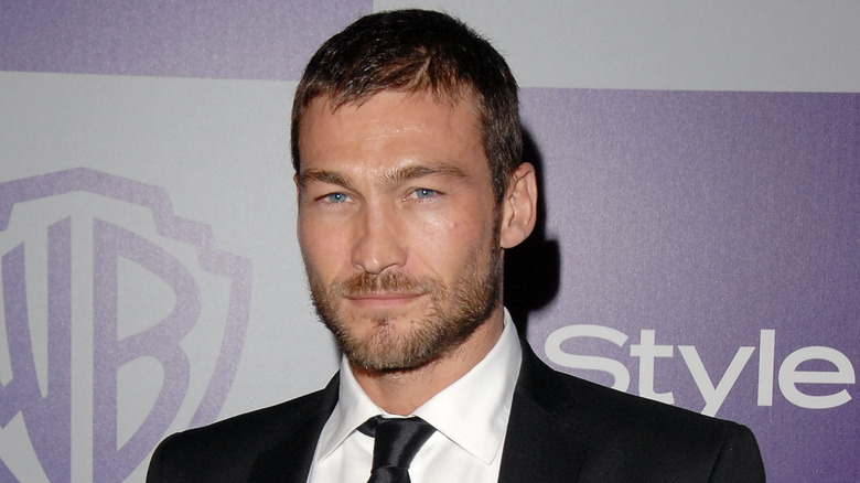 Andy Whitfield wearing a black suit and black tie