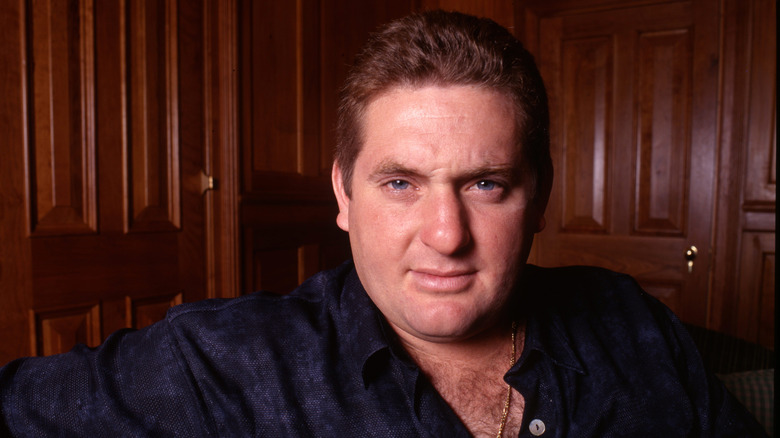 Chris Penn wearing a blue patterned button down shirt and gold chain