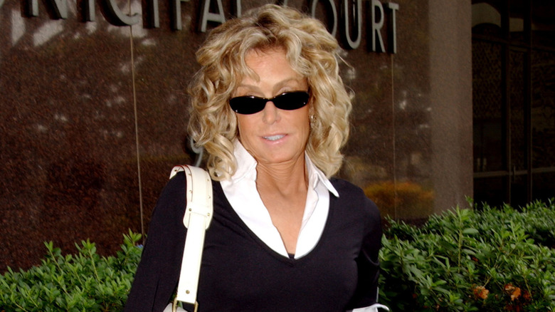 Farrah Fawcett wearing black sunglasses, a white collared shirt and black sweater