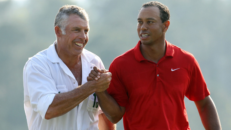 Steve Williams and Tiger Woods handshaking and smiling out on the golf course