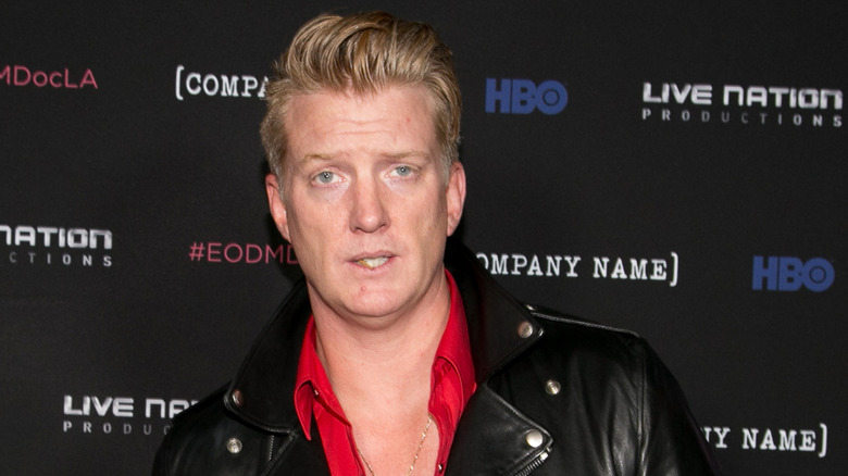 Josh Homme in a leather jacket and red button up shirt