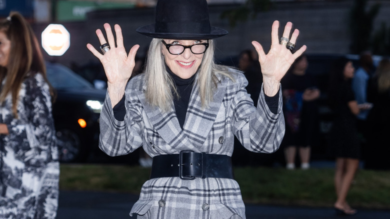 Diane Keaton posing animatedly at fashion week.