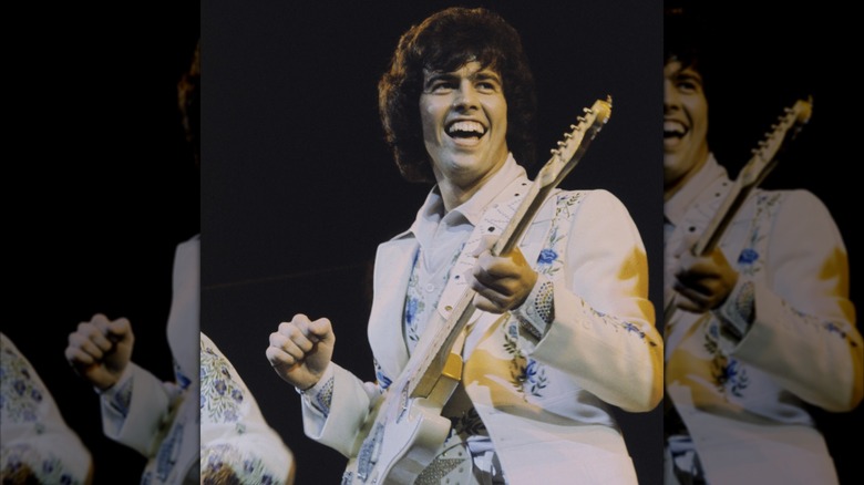 Alan Osmond playing guitar on stage