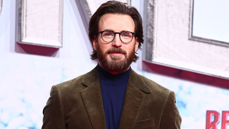 Chris Evans with glasses and a beard posing in front of a white background