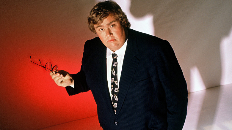 John Candy holding a pair of glasses in a photo portrait