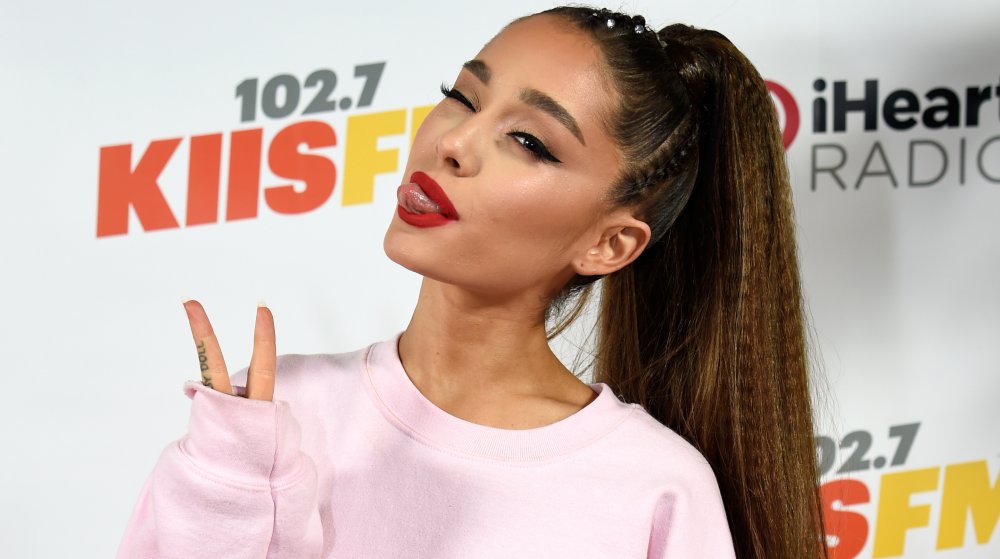 Ariana Grande with her signature ponytail, throwing up a peace sign