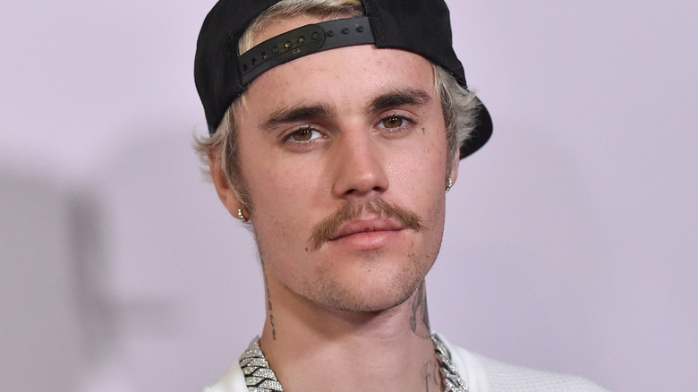 Justin Bieber wearing a black cap and diamond chain