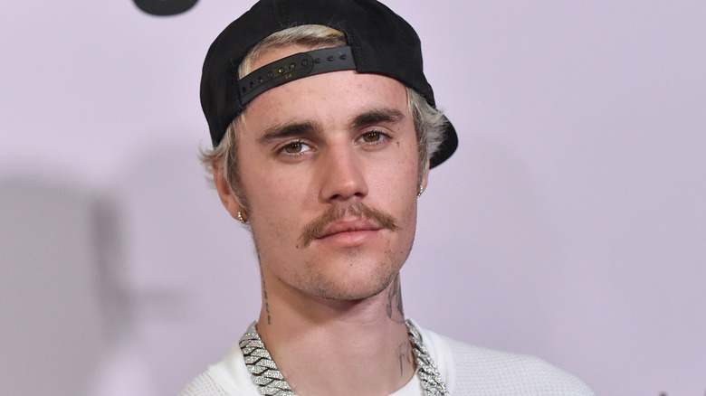 Justin Bieber wearing a black cap and diamond chain