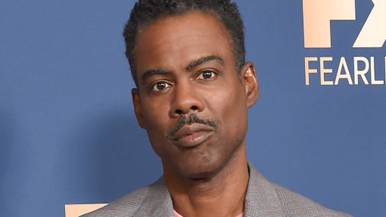 Chris Rock posing in a grey suit