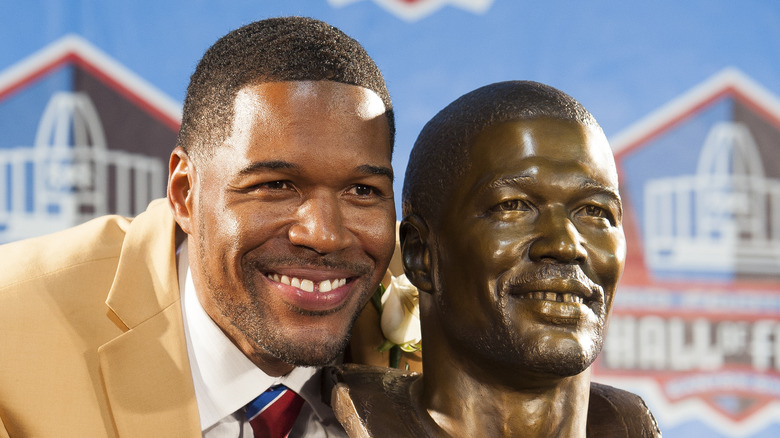 Michael Strahan smiling next to bust of himself