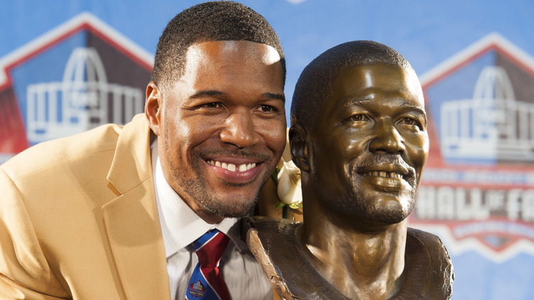 Michael Strahan smiling next to bust of himself