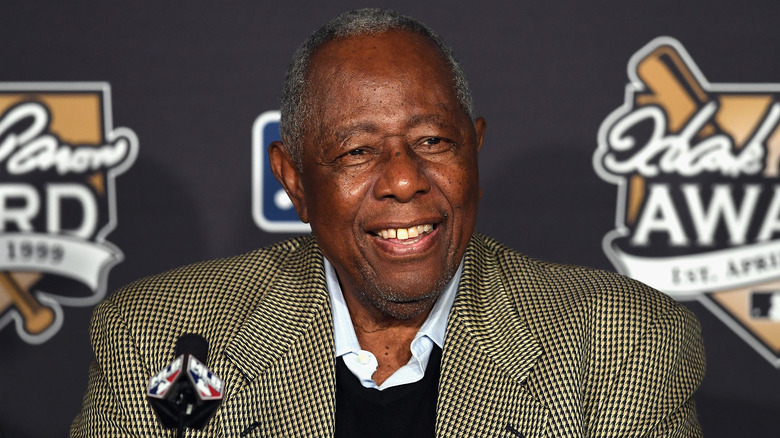 Hank Aaron smiling behind microphone