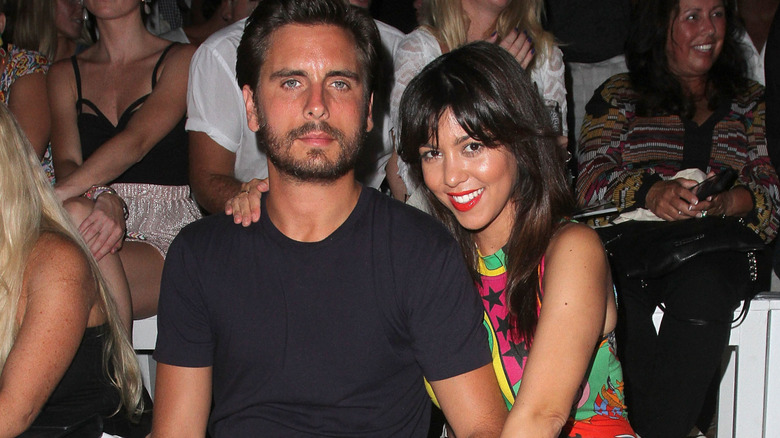 A stonefaced Scott Disick next to a smiling Kourtney Kardashian