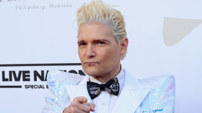 Corey Feldman with blond hair pointing