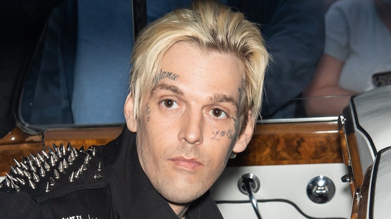 Aaron Carter leans toward an instrument while facing away from the camera