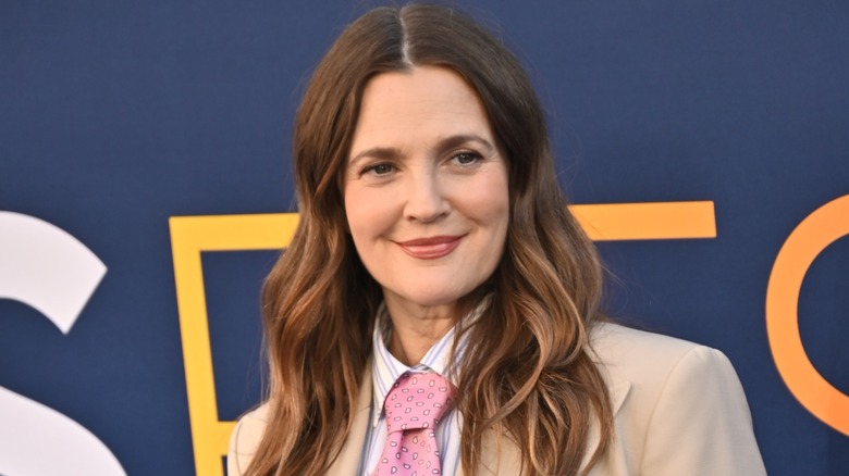 Drew Barrymore rocks a tan suit as she smiles while facing away from the camera