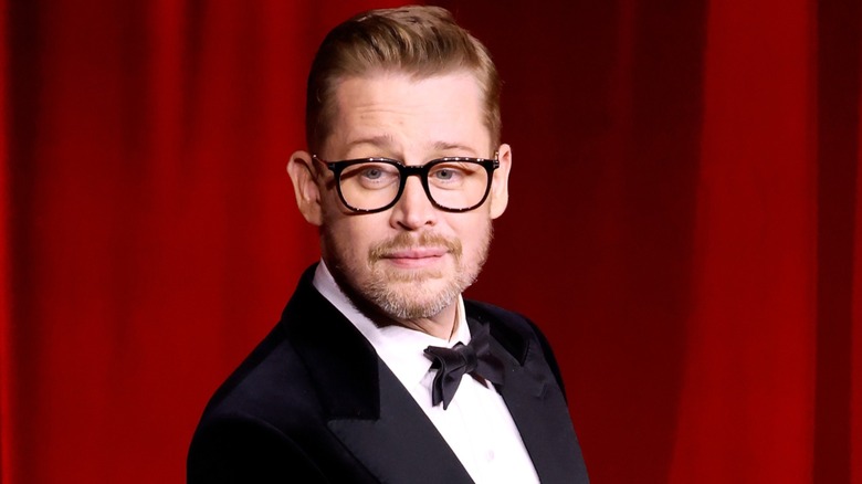Dressed in a black tuxedo, Macaulay Culkin gazed downward while posing sideways