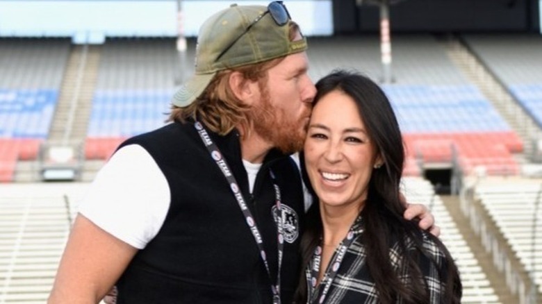 Chip Gaines in baseball hat kissing wife Joanna