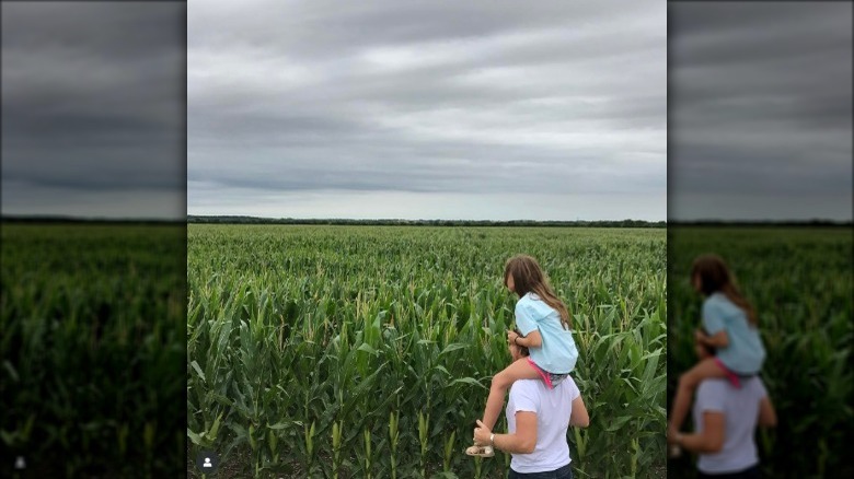 Kid being carried on shoulders in large corn field
