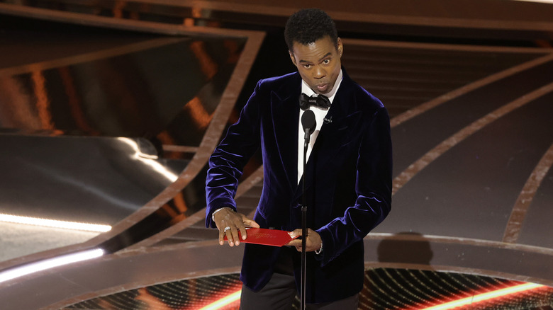 Chris Rock on Oscars stage holding envelope